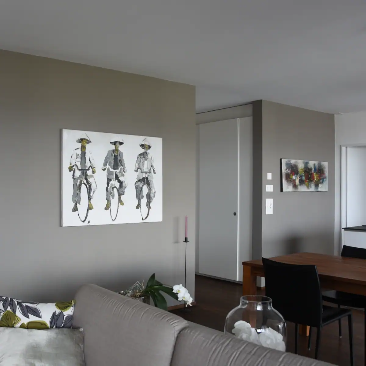 Farbgestaltung Wohnung: Ess- und Livingbereich mit Längswand in Umbra, darauf zwei harmonisch abgestimmte Bilder. Das Umbra gleicht die übrigen Flächen in Weiss aus.