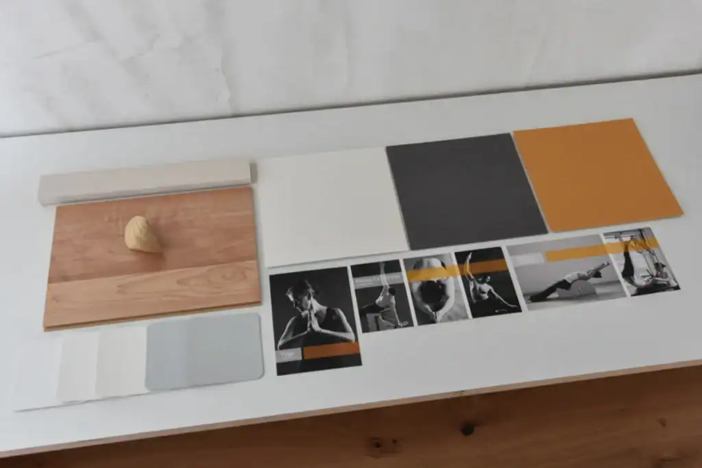 Farbkonzept für ein Yoga- und Pilatesstudio basierend auf den Werbepostkarten (Schwarzweiss-Aufnahmen mit halbtransparentem Streifen in Hellgrau und Ocker). Die Präsentation mit Mustern zeigt Schattierungen von Weiss, Hellgrau, rötlichem Ockergelb und Anthrazit für die Wände. Sie harmonieren mit dem hellbraunen Laminatboden.