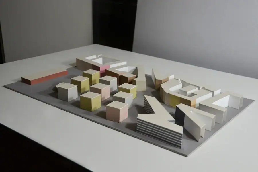 Präsentationsmodell für die Fassadengestaltung einer Siedlung von neun Wohnblöcken im städtischen Umfeld (Studienprojekt). Das Modell zeigt 9 kubische Blöcke in drei sanften warmen Farben: 3 hellgraue, 4 gelbgrüne und 3 rosa Blöcke. Die Farben harmonieren mit der Farbigkeit des Kontextes.