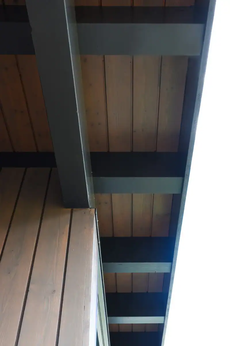 Eingangsbereich mit Treppenhaus im Einfamilienhaus aus den 50er-Jahren. Links rote Wand, hellbeige Bodenplatten und Treppentritte, übrige Wände in abgetöntem Weiss. Unterhalb der Treppe am Boden zwei Kugellampen, die eine warme Atmosphäre ausstrahlen.