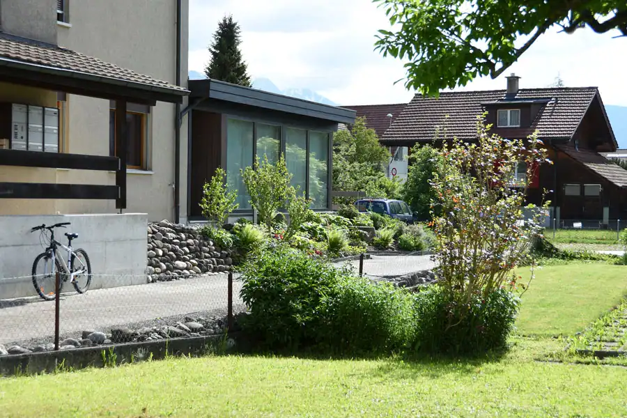 Blassgrüne Fassade eines Einfamilienhauses aus den 50er-Jahren in grüner Quartierumgebung.
