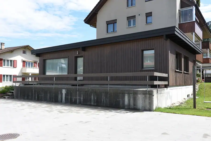 Blassgrüne Fassade eines Einfamilienhauses aus den 50er-Jahren in grüner Quartierumgebung.