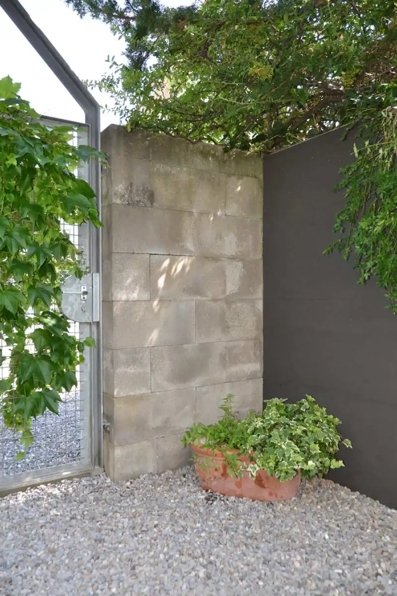 Studio für Yoga und Pilates. Personal-Trainingsraum. Blick von der Nordwand Richtung Akzentwand in Mauveanthrazit. Linke Wand zum Gruppentrainingsraum in Weiss, Tür hellgrau. Rechts Westwand in Weiss mit grossen Fenstern. Mitteldunkler honigfarbener Laminatboden und helle Holzdecke. Im Raum stehen verschiedene Pilates-Trainingsgeräte in hellem Holz und mit mittelgrauen gepolsterten Liege- und Sitzflächen. Die Anthrazitwand gibt dem Raum Halt und klare Orientierung.