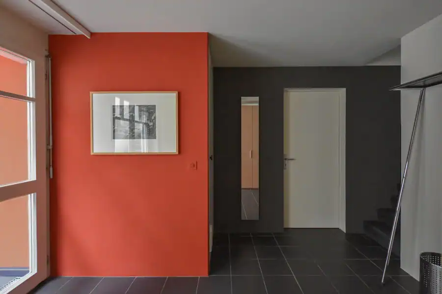 Schlafzimmer Gestaltung. Bemusterung mit Musterplatten in Originalfarbe und -material: Tapete mit floralem Muster in hellschimmerndem Grau vor tiefengrauem Hintergrund, Daneben Musterplatten der Wandfarben in tuchmattem, dunklem, rauchigem Blaugrau und hellem, warmen Muschelkal, sowie Farbakzent in Herbstgold. Leiste des dunkelbraunen Parketts.