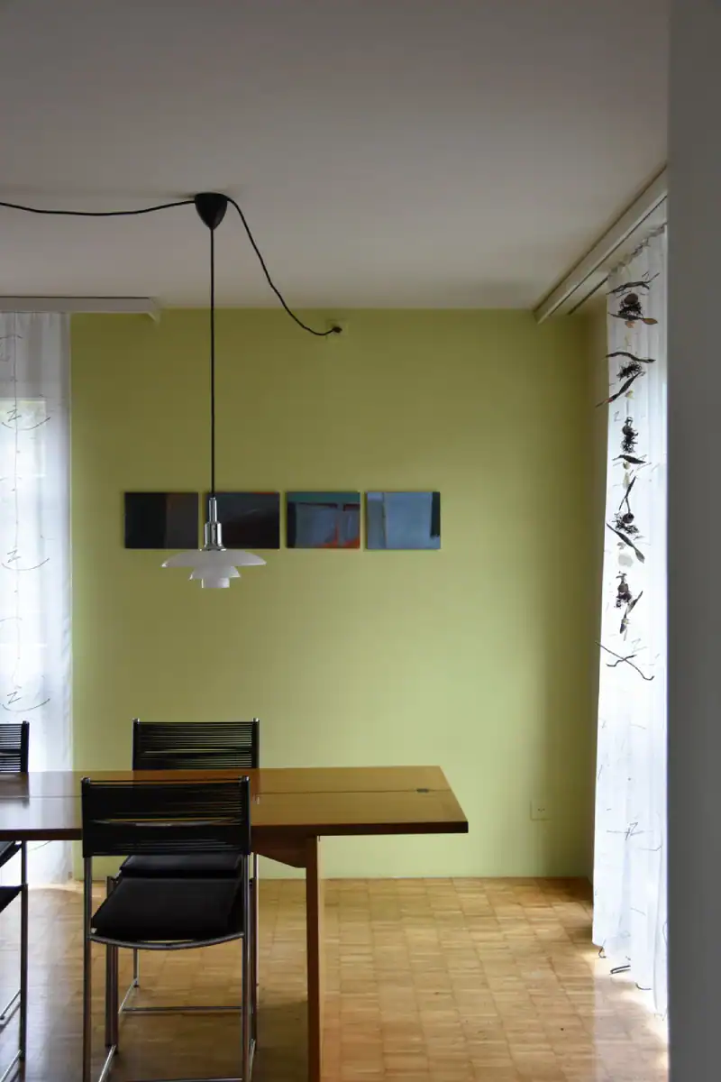 Schlafzimmer Gestaltung. Blick zur Nordostecke mit der Nische. Rechts ist ein Teil des hochwertigen dichten Vorhanges mit Silber-Bronze-Ornamenten. Links die helle Muschelkalkwand mit einer grossen hochformatigen Nische in Herbstgold, deren Boden im selben dunkelnbrauen Holz wie der Parkettboden beschaffen ist.
