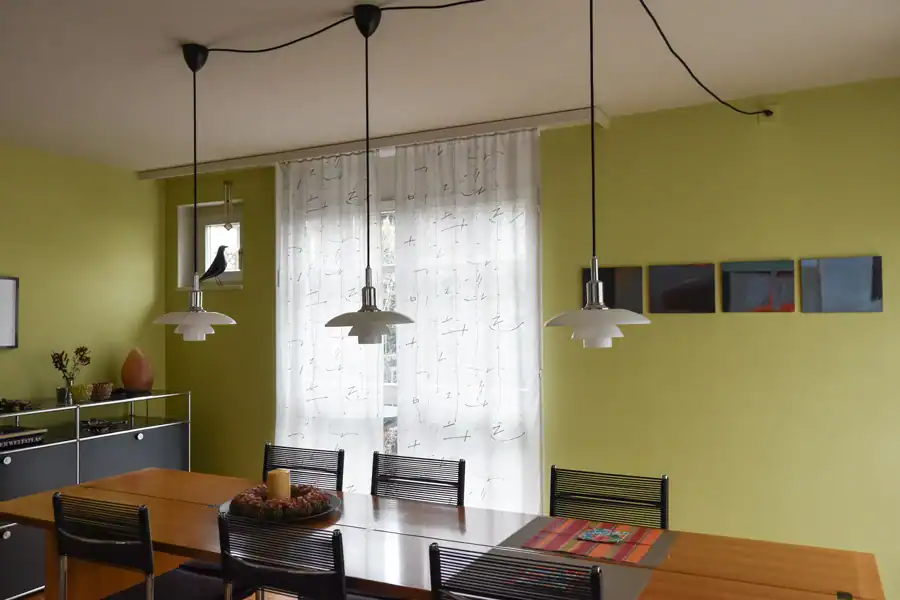 Bemusterung für eine Farbgestaltung: Zusammenspiel von einem dunklen Farbmuster in Rauchblau für die Wand und einem blauen Vorhang mit Silberornamenten.