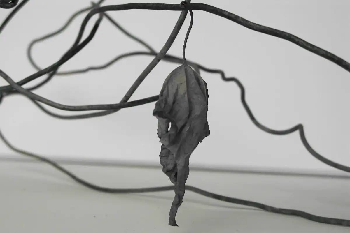 Detail der Treppenhausgestaltung im Einfamilienhaus aus den 50er-Jahren. Schräge Sicht nach oben ins Obergeschoss. Links Akzentwand in Rot, die vom Eingang bis ins Obergeschoss leitet, übrige Wände in abgetöntem Weiss. Treppentritte in hellbeigen Steinplatten, Betonunterteil in abgetöntem Weiss, schwarze Metallbrüstung. An der Rückwand ein quadratisches Bild mit kreisförmigem Motiv in Weiss, Orange und Blau auf tiefdunklem rotviolettem Hintergrund. Klare, reduzierte Architektursprache, die aus den Kontrasten lebt.