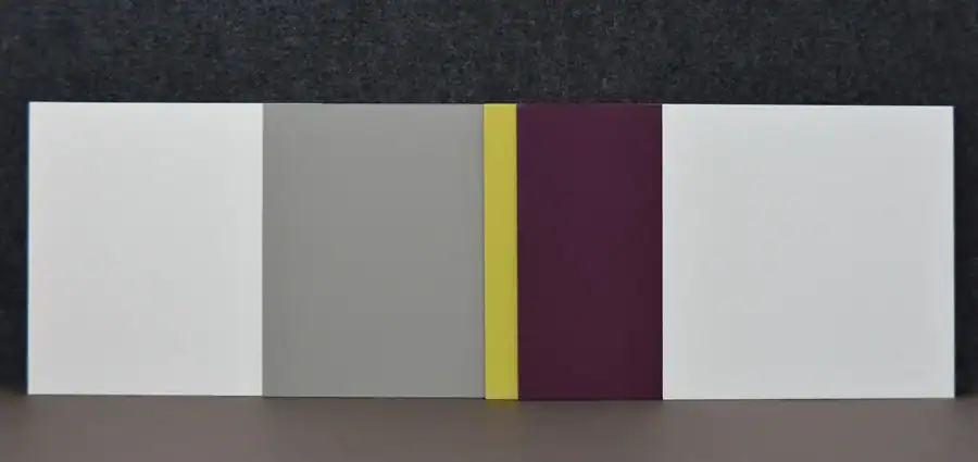 Schlafzimmer Gestaltung. Bemusterung mit Musterplatten in Originalfarbe und -material: Tapete mit floralem Muster in hellschimmerndem Grau vor tiefengrauem Hintergrund, Daneben Musterplatten der Wandfarben in tuchmattem, dunklem, rauchigem Blaugrau und hellem, warmen Muschelkal, sowie Farbakzent in Herbstgold. Leiste des dunkelbraunen Parketts.