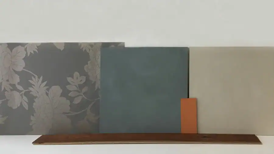 Schlafzimmer Gestaltung. Bemusterung mit Musterplatten in Originalfarbe und -material: Tapete mit floralem Muster in hellschimmerndem Grau vor tiefengrauem Hintergrund, Daneben Musterplatten der Wandfarben in tuchmattem, dunklem, rauchigem Blaugrau und hellem, warmen Muschelkal, sowie Farbakzent in Herbstgold. Leiste des dunkelbraunen Parketts.