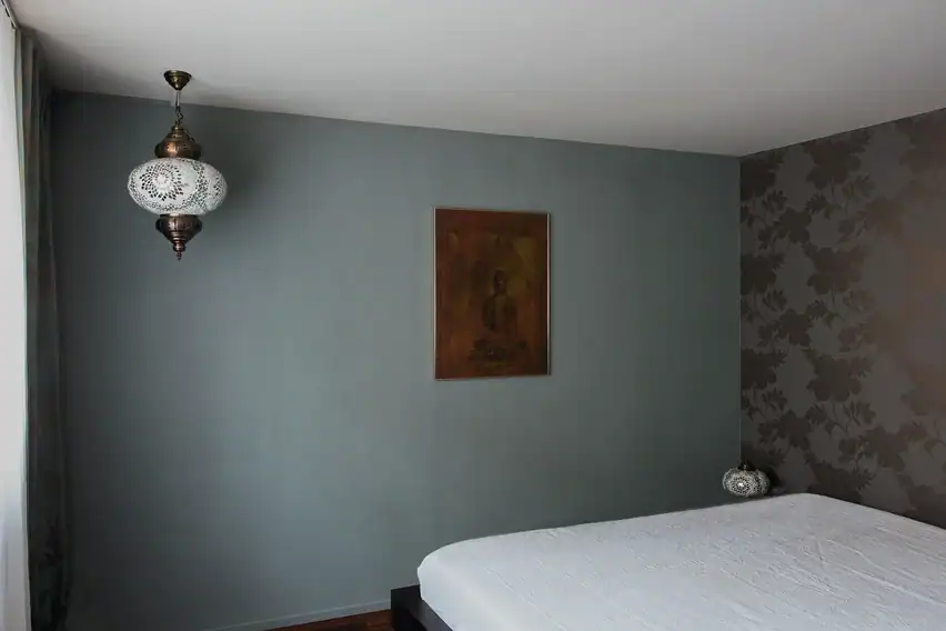 Bemusterung für eine Farbgestaltung: Zusammenspiel von einem dunklen Farbmuster in Rauchblau für die Wand und einem blauen Vorhang mit Silberornamenten.