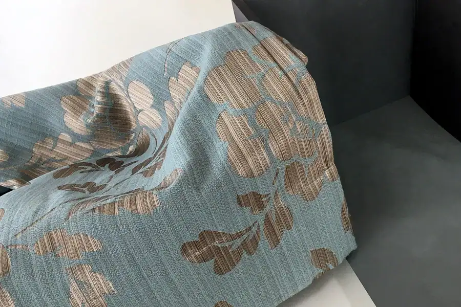 Schlafzimmer Gestaltung. Detailbild: Blaugrauer Vorhang mit Silber-Bronze-Ornamenten. Daneben Farbmuster der Wandfarbe in tuchmattem, dunklem, rauchigem Blaugrau.
